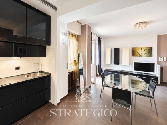 Cucina e soggiorno con tavolo in vetro nel trilocale di Via Vittorio Veneto ad Arona